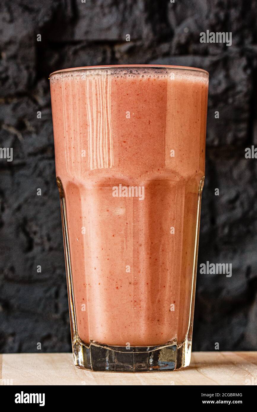 Smoothie aux agrumes d'orange dans un grand verre contre un mur en pierre sombre Banque D'Images