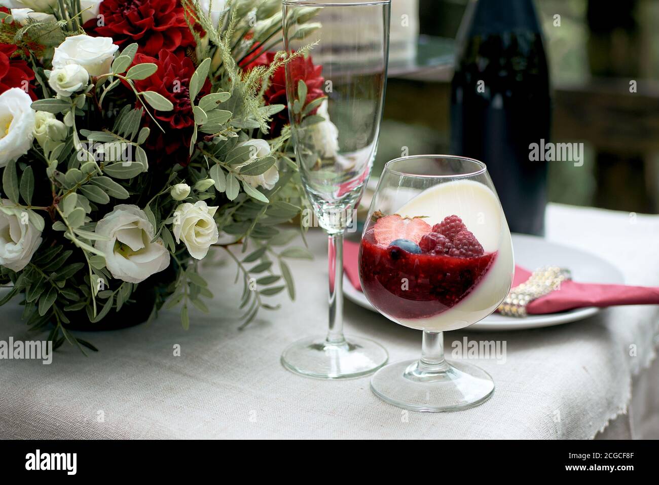Fragment de la table de fête. Dessert crémeux léger avec fraises, bleuets et salina. Composition de fleurs fraîches chresanthème, amion et euc Banque D'Images
