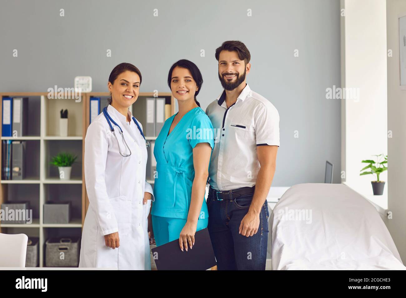 Portrait de groupe de trois jeunes professionnels de la santé souriants dans moderne bureau de la clinique Banque D'Images