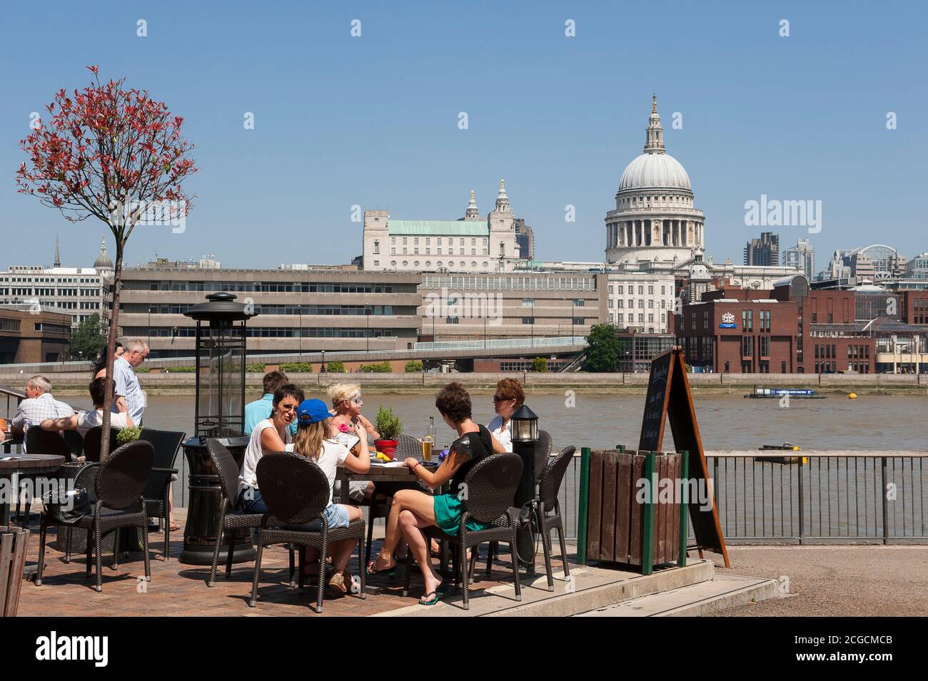 Les gens déjeunent en plein air sur la rive sud de la Tamise, avec la cathédrale St Paul au loin, Londres, Angleterre. Banque D'Images