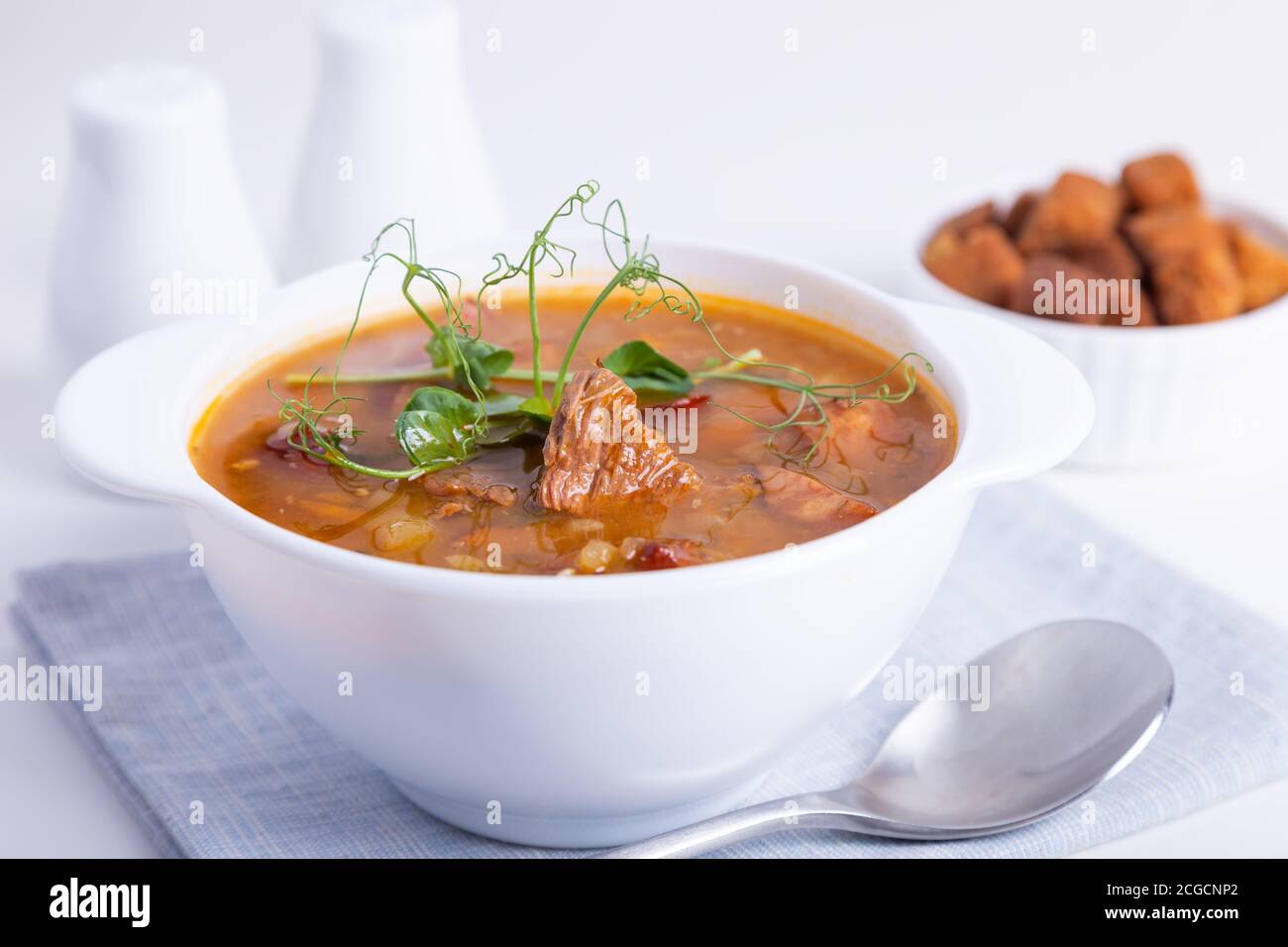 Soupe aux pois avec viande, saucisse fumée, pousses de pois et croûtons. Plat russe traditionnel. Cuisine maison. Gros plan, mise au point sélective. Banque D'Images