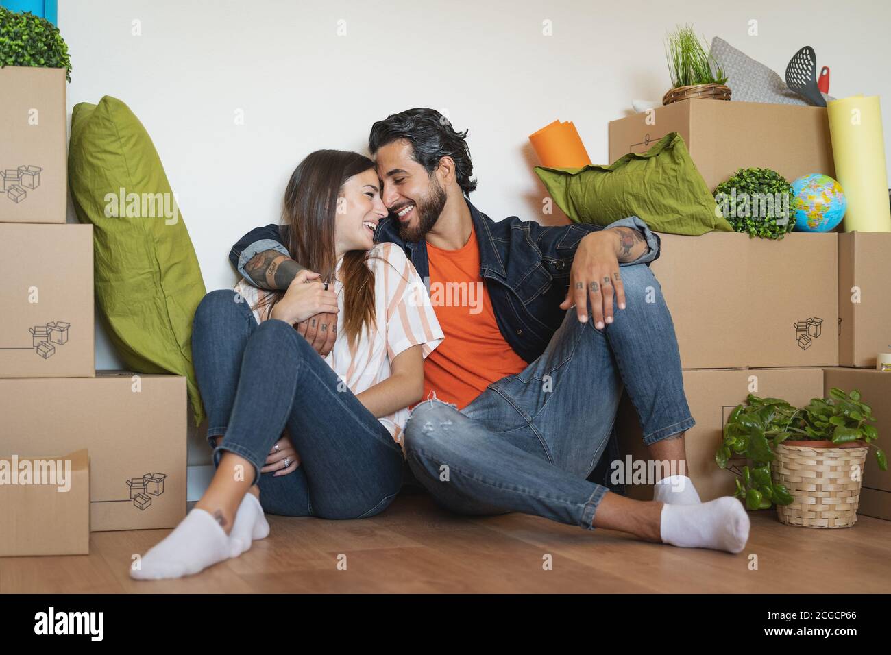 Heureux jeune couple se déplaçant dans la nouvelle maison la première fois - l'homme et la femme ayant plaisir déballage carton boîte dans la nouvelle maison de propriété Banque D'Images