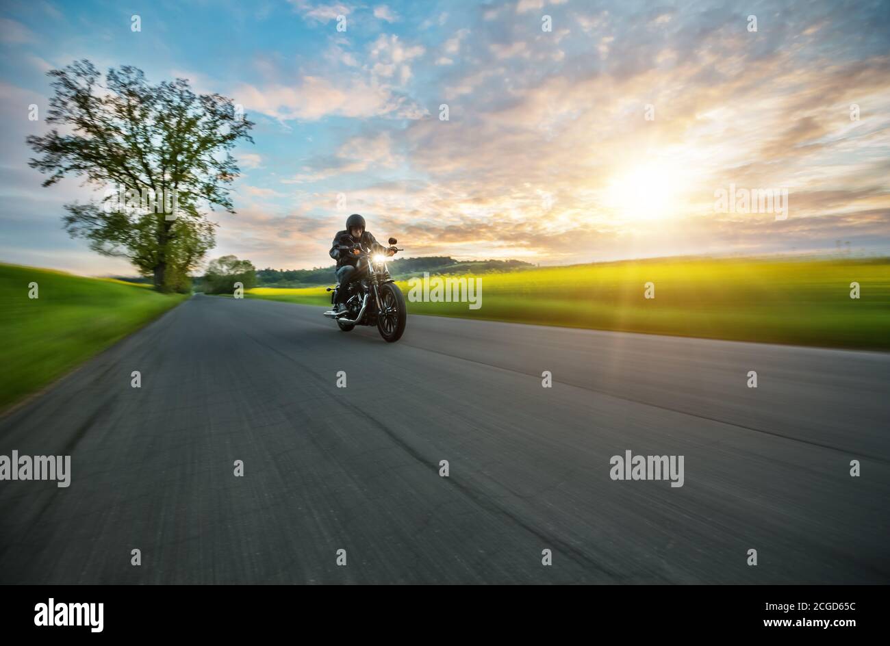 Moto sombre qui fait de la moto haute puissance dans la nature avec une belle lumière de coucher de soleil. Voyages et transport. La liberté de la moto Banque D'Images