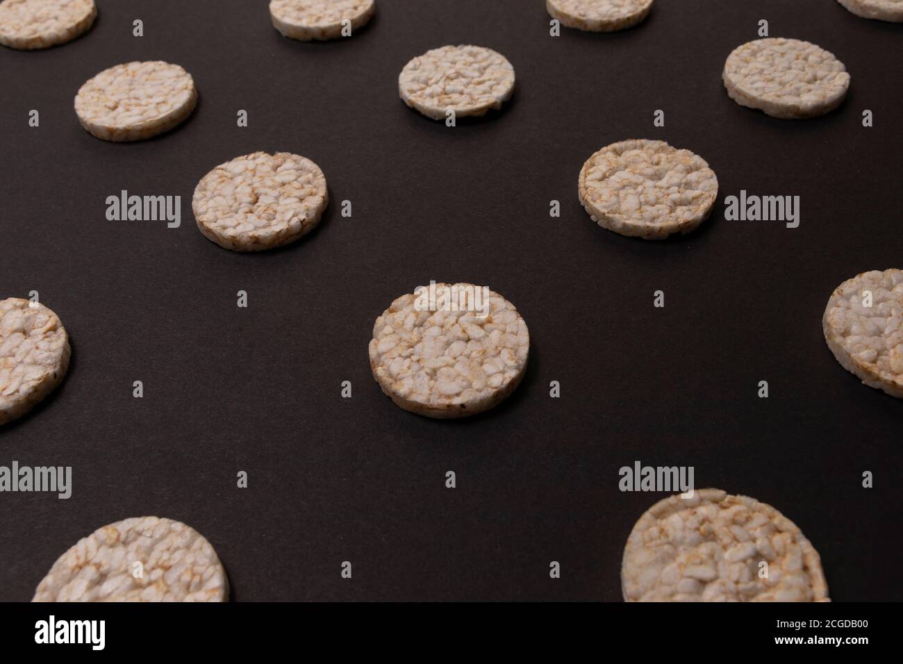 Répartition des pattern de crackers de riz. Craquelins ronds de riz, étaler sur fond noir. Conception avant ou perspective. Photographie de faible intensité. Banque D'Images