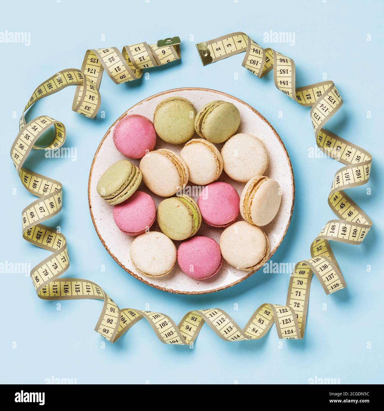 Plaque complète de macarons sur la table avec un mètre ruban, vue de dessus. Concept de régime Banque D'Images