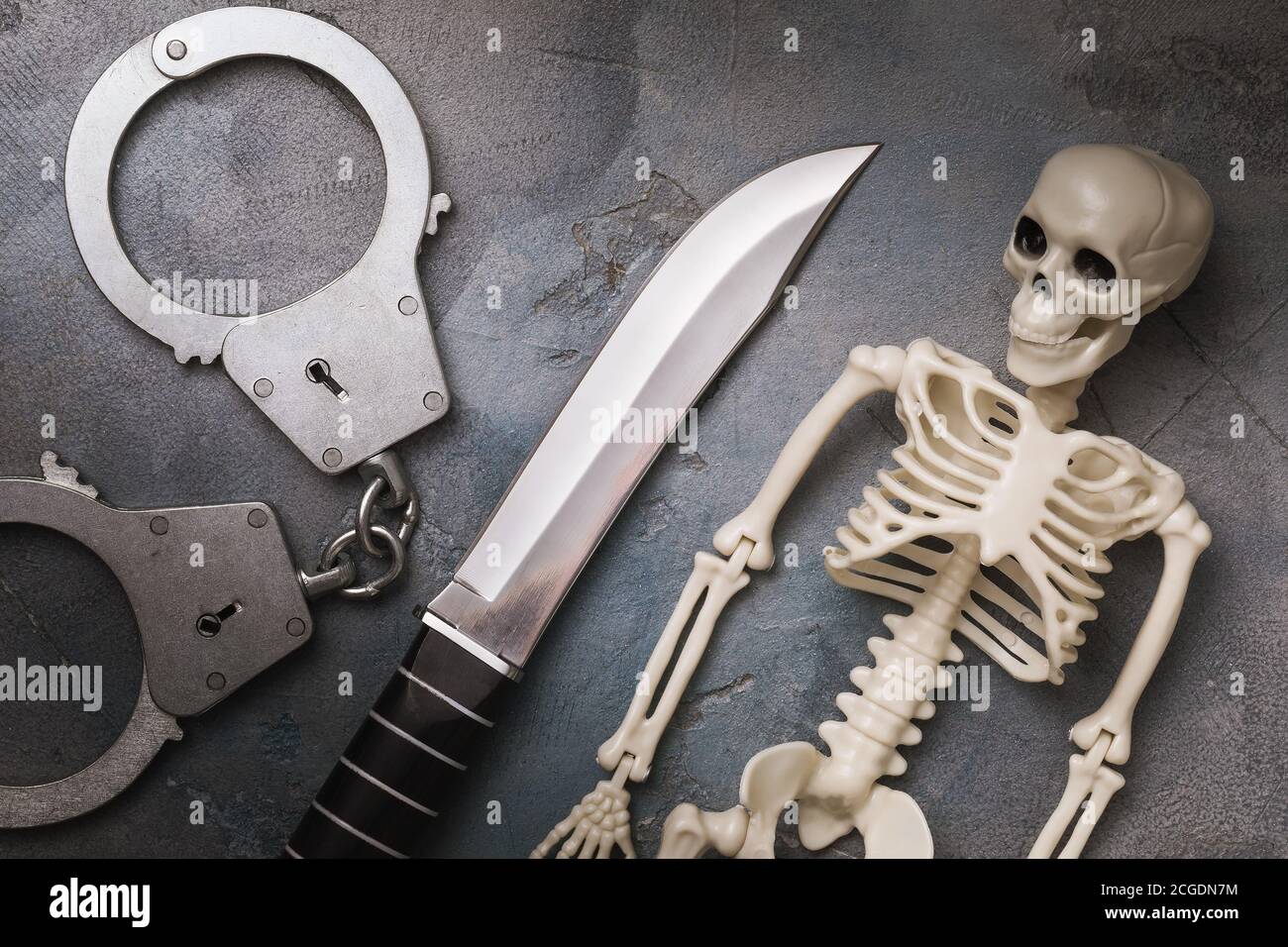 Menottes, couteau et squelette humain, vue du dessus. Concept de punition pour le crime Banque D'Images