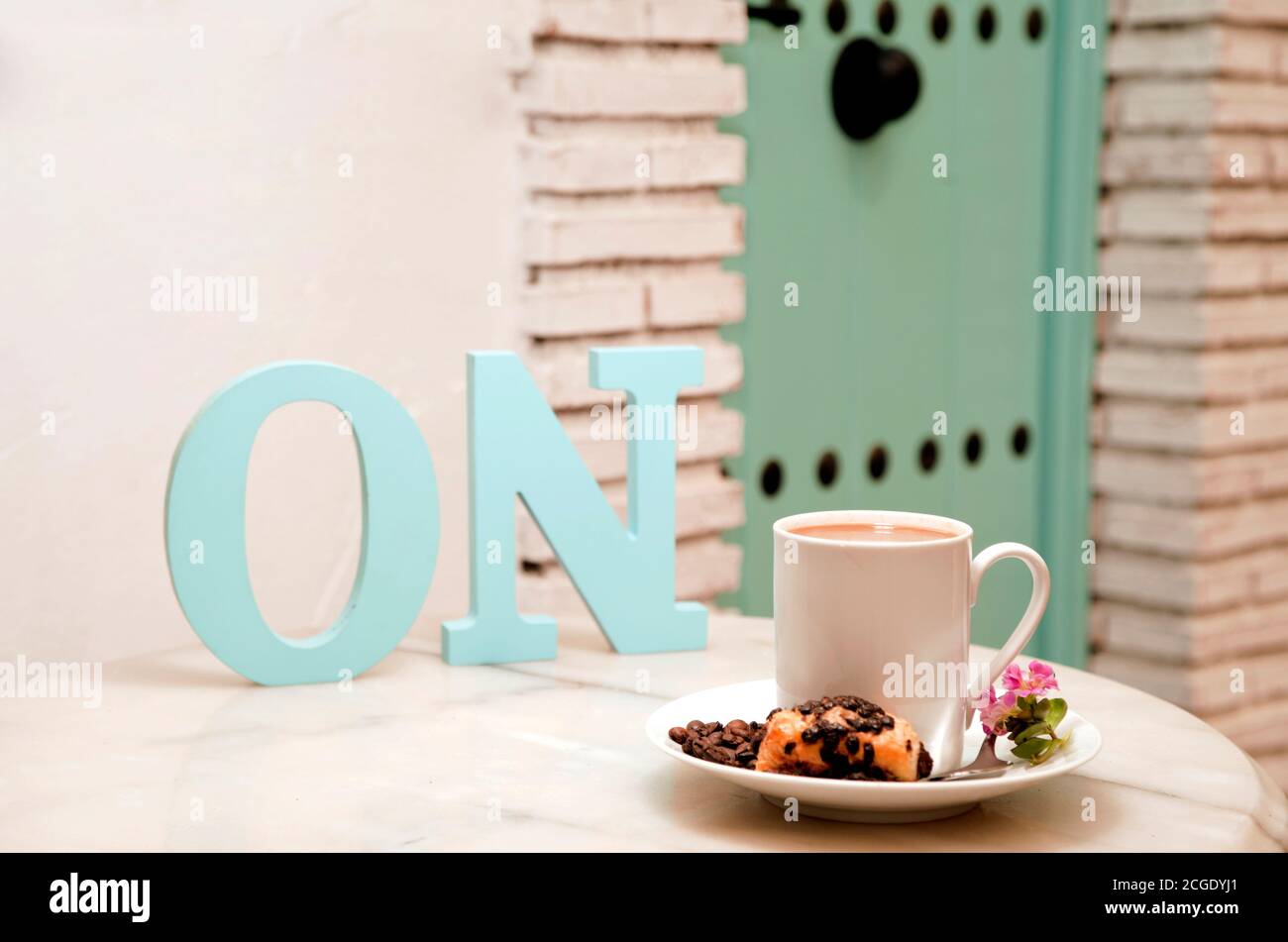 Activer concept, (lettres SUR) tasse de café avec doux, sur table en marbre, avec pâtisseries dans le panier en osier, et fond de la maison méditerranéenne, espace Banque D'Images
