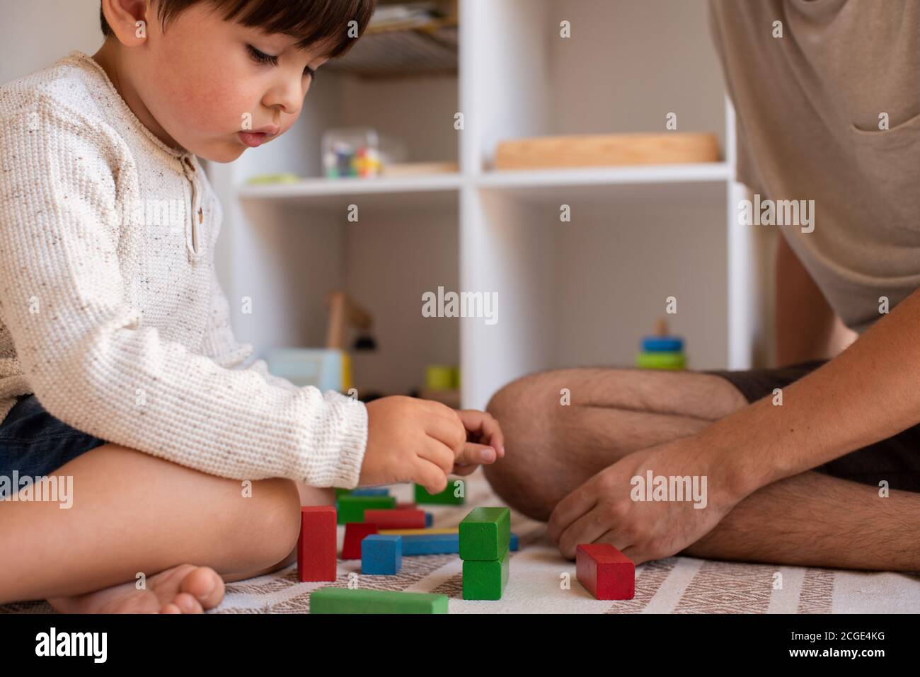 Petit enfant et son père jouant à la maison avec des blocs de construction en bois. Homeschooling. Restez à la maison. Temps en famille Banque D'Images