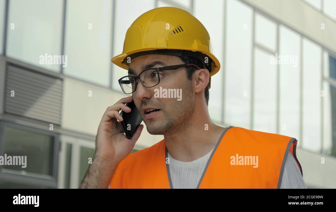Inspecteur d'ingénieur nerveux dans hardhat parlant au téléphone. Banque D'Images