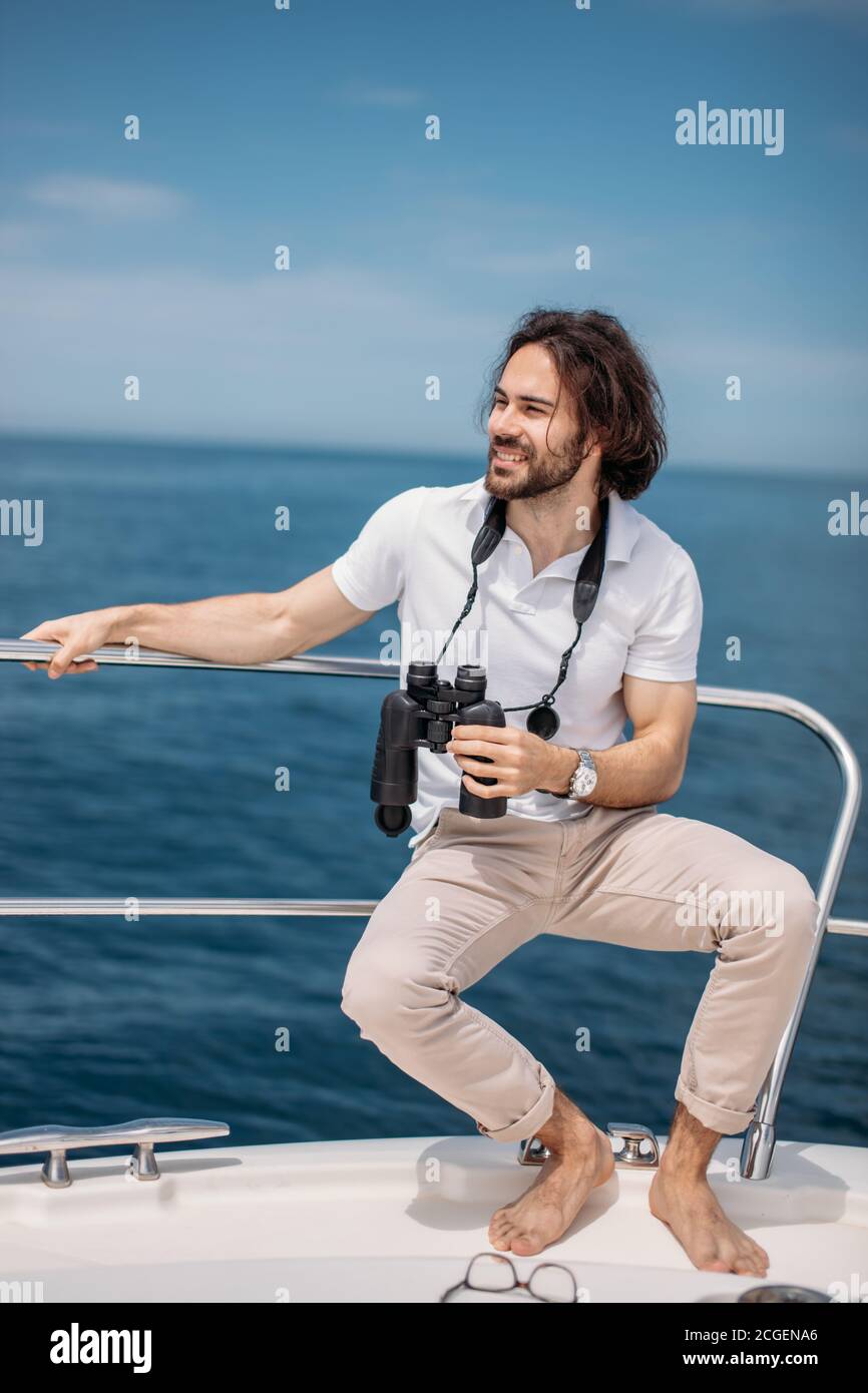 Voyageur barbu de race blanche homme regardant à travers les jumelles de la voile, adorant la beauté et la puissance de l'Océan Banque D'Images