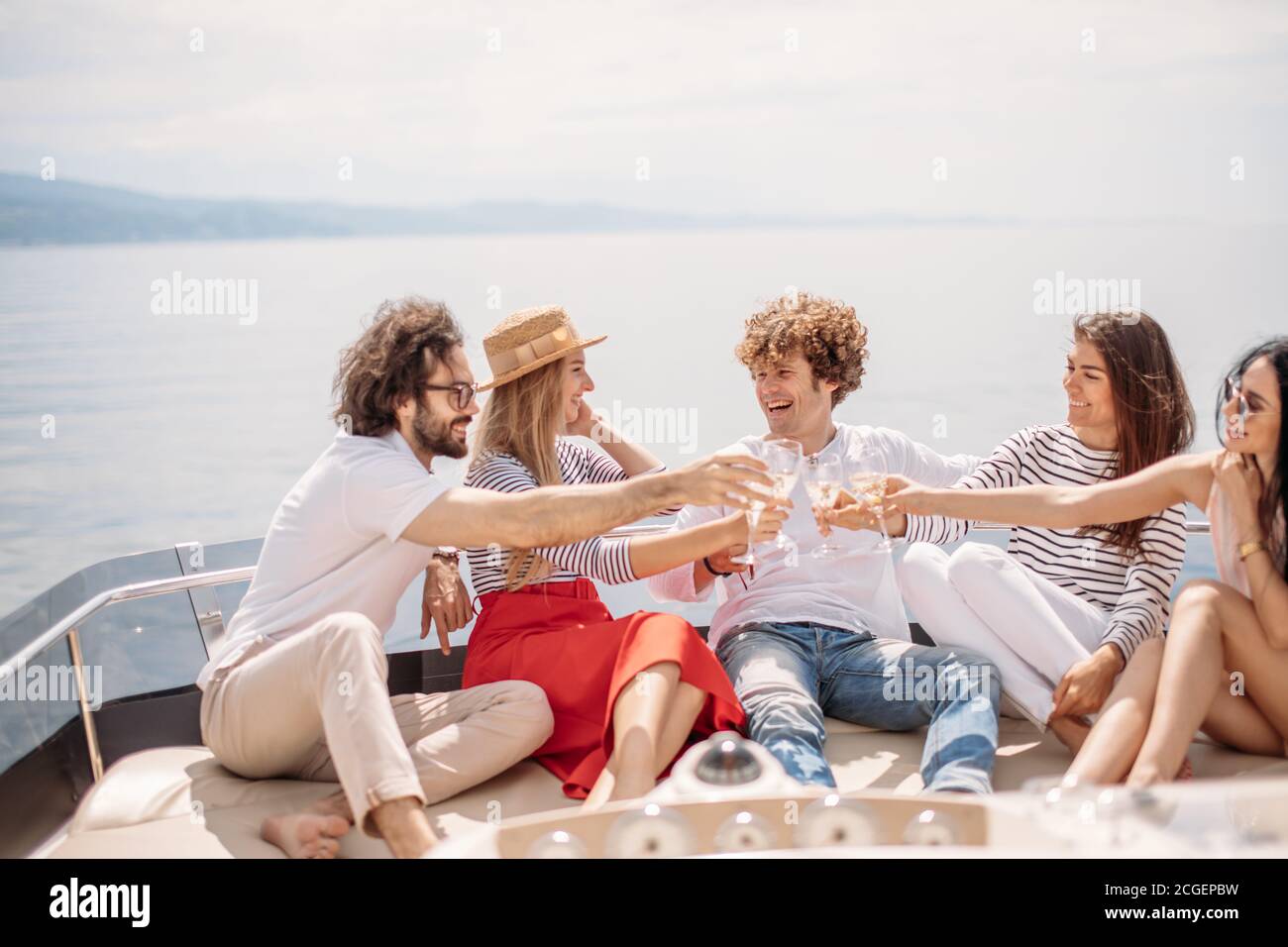 Les jeunes touristes européens les gars et les filles de célébrer le début de leur heureux location vacances - Groupe de friends toasting drinks et avoir des parties sur un sai Banque D'Images