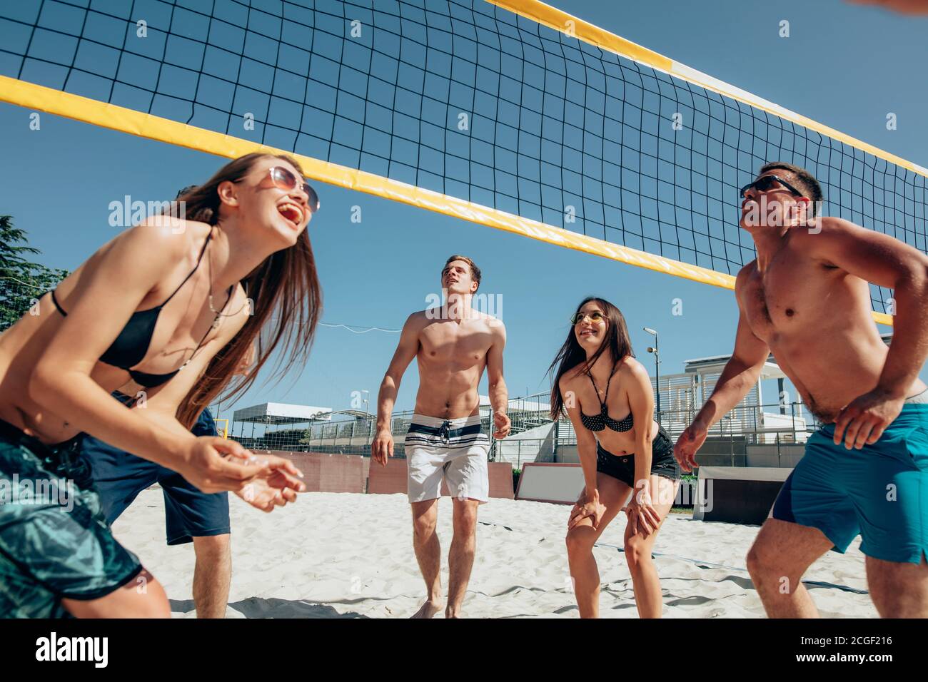 Groupe de jeunes hommes et femmes jouant au Beach-volley sur le sable. Vacances d'été, sport, jeux et amitié concept - jouer à valhesen plein air Banque D'Images