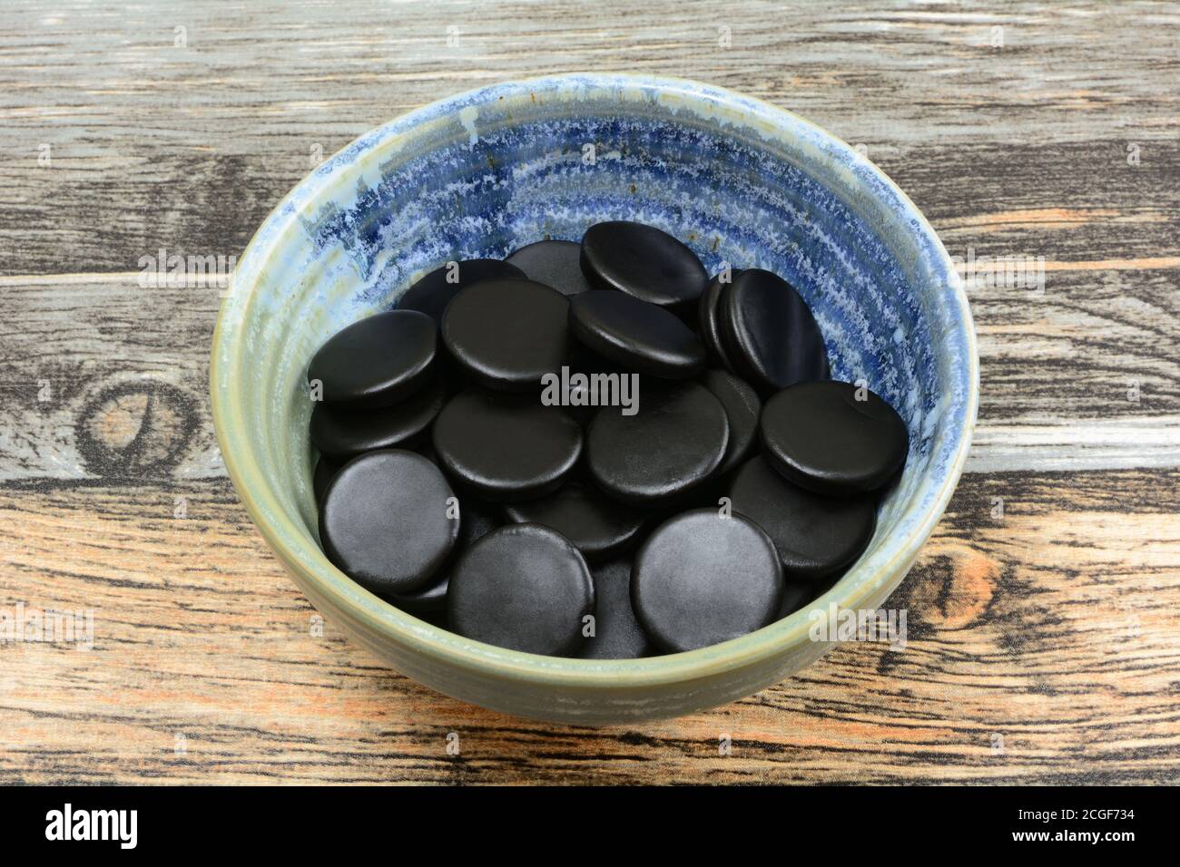 Ronds de bonbons à la réglisse noirs dans un petit bol en céramique tableau Banque D'Images