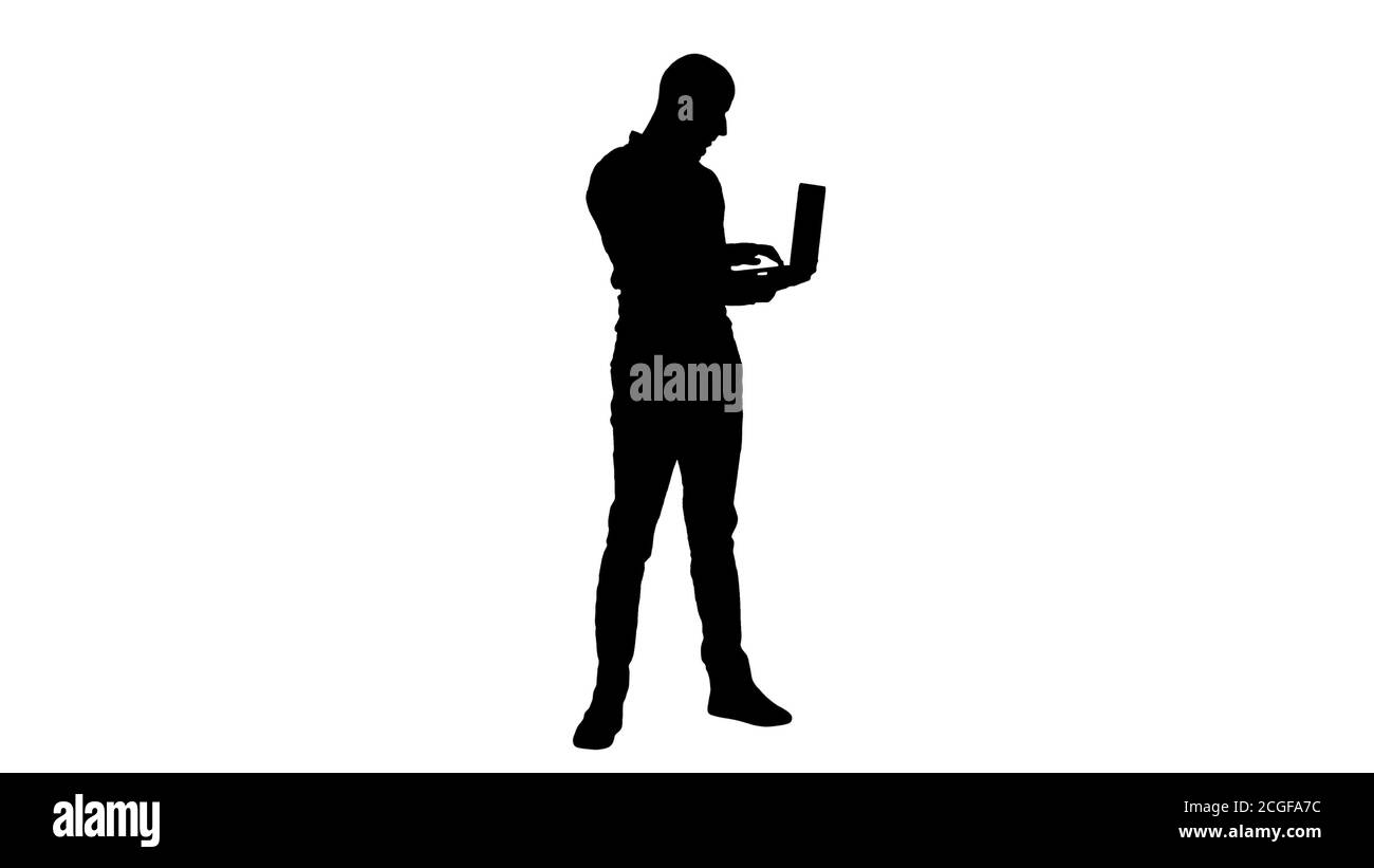 Silhouette Young homme d'affaires du Moyen-Orient, debout et dactylographiant sur un ordinateur portable en le tenant dans ses mains. Banque D'Images