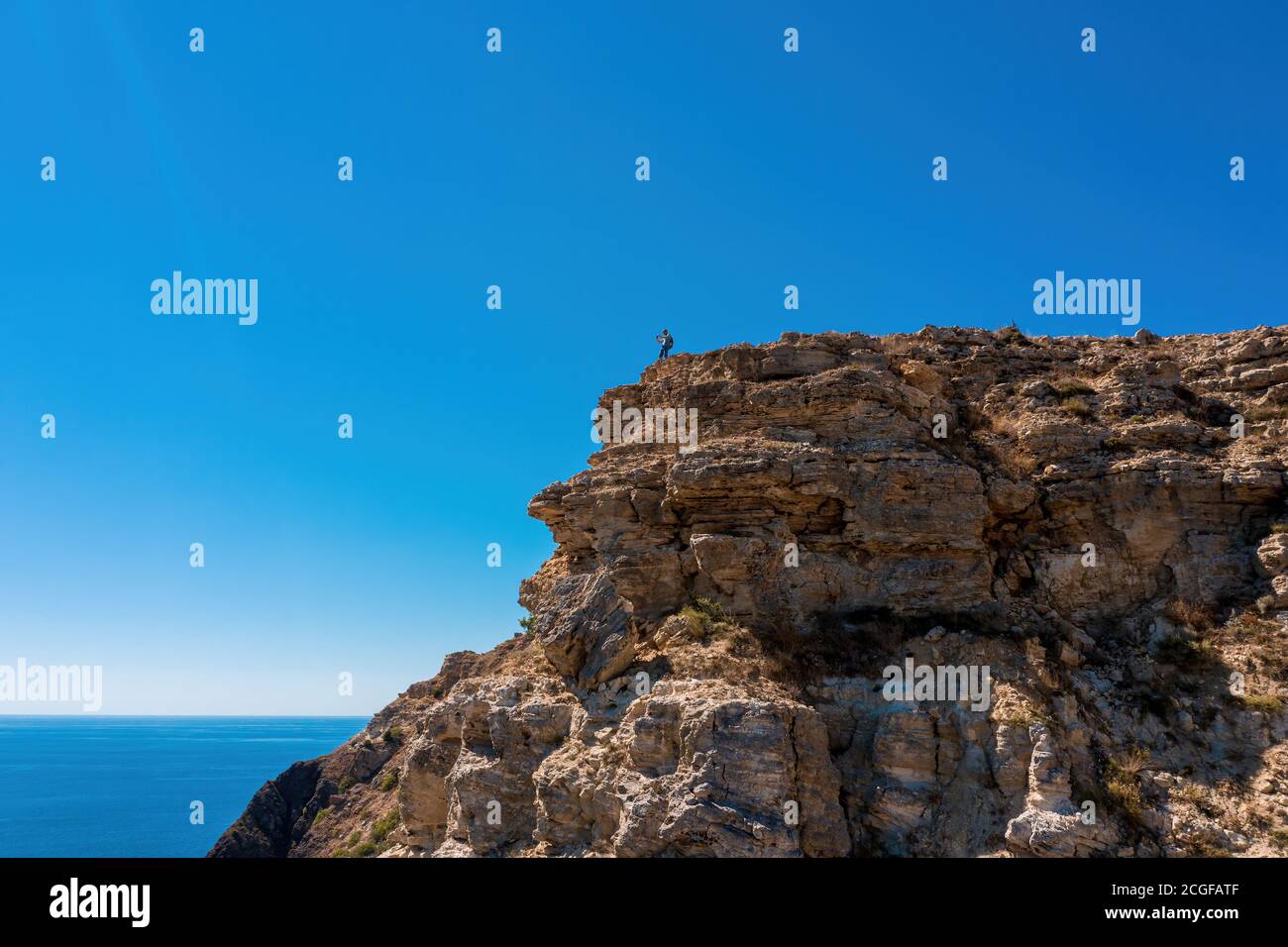 Un homme se tient sur un promontoire élevé et regarde la mer. Photo de haute qualité Banque D'Images