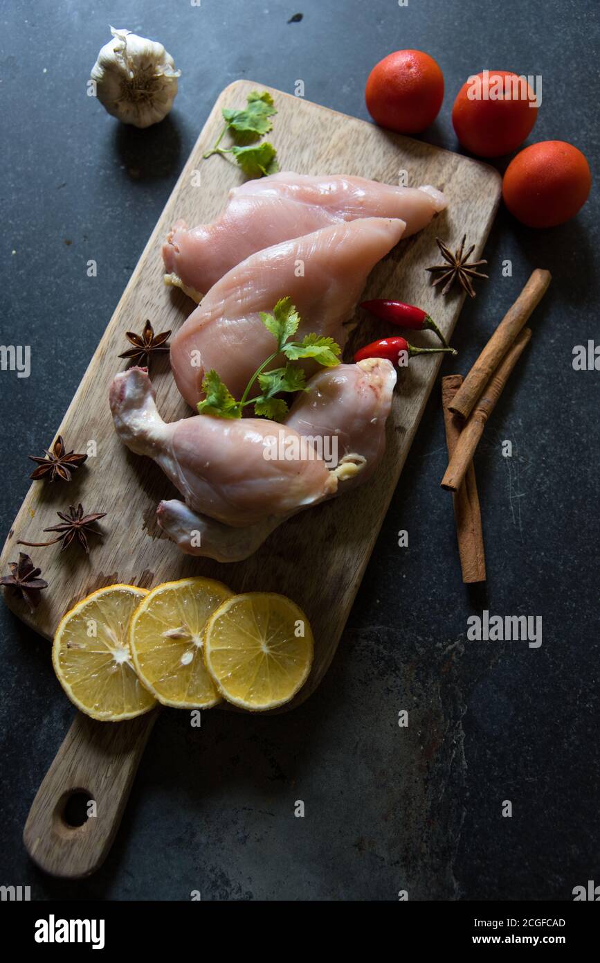 Vue de dessus des cuisses de poulet crues avec condiments sur un plateau sur fond noir Banque D'Images