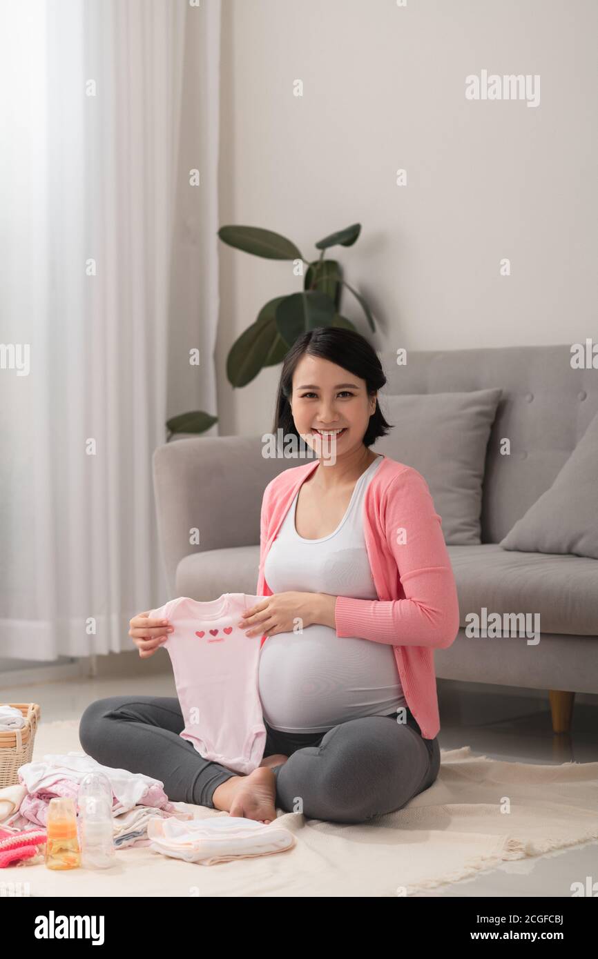 Belle femme asiatique enceinte emballage et préparation des vêtements de bébé dans le panier pour le nouveau-né Banque D'Images