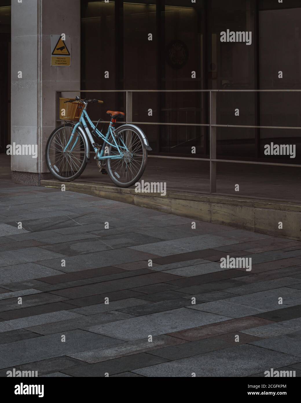 Un vélo bleu solitaire appuyé contre les rampes à l'extérieur de Manchester Crown Cour Banque D'Images