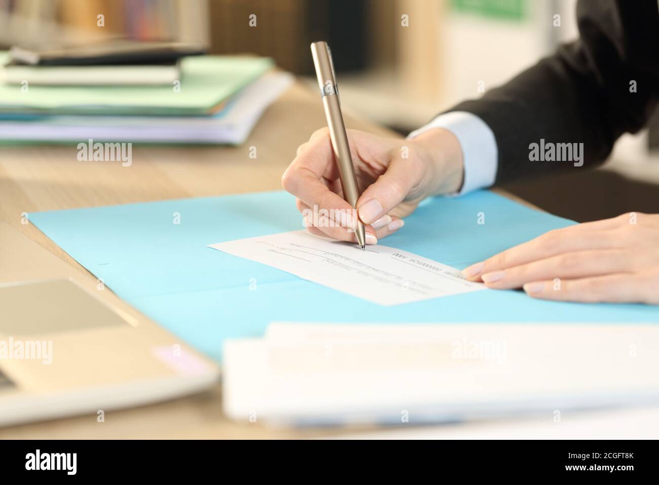 Gros plan de la femme autonome mains signant le chèque de banque assis à la maison Banque D'Images