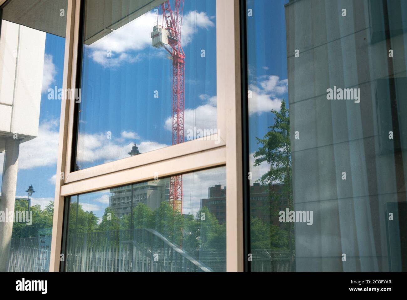 Une fenêtre à Londres reflétant une grande grue rouge sur un chantier de construction. Banque D'Images
