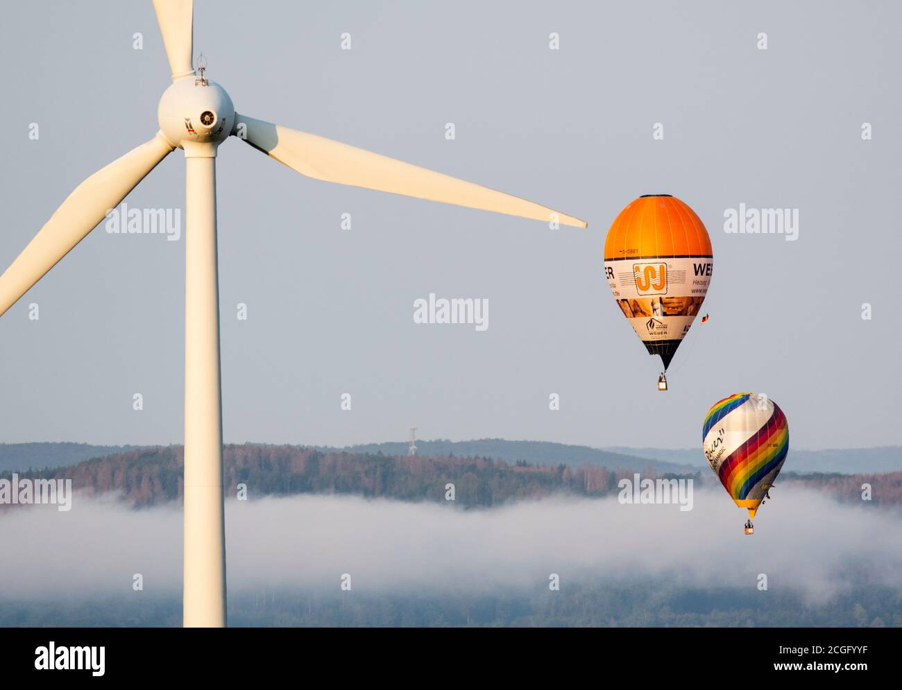 11 septembre 2020, Rhénanie-du-Nord-Westphalie, Möhnesee : deux ballons à  air chaud survolent une éolienne au-dessus du brouillard matinal. Après un  lancement en extérieur, plus de 20 ballons avaient été retirés de sites