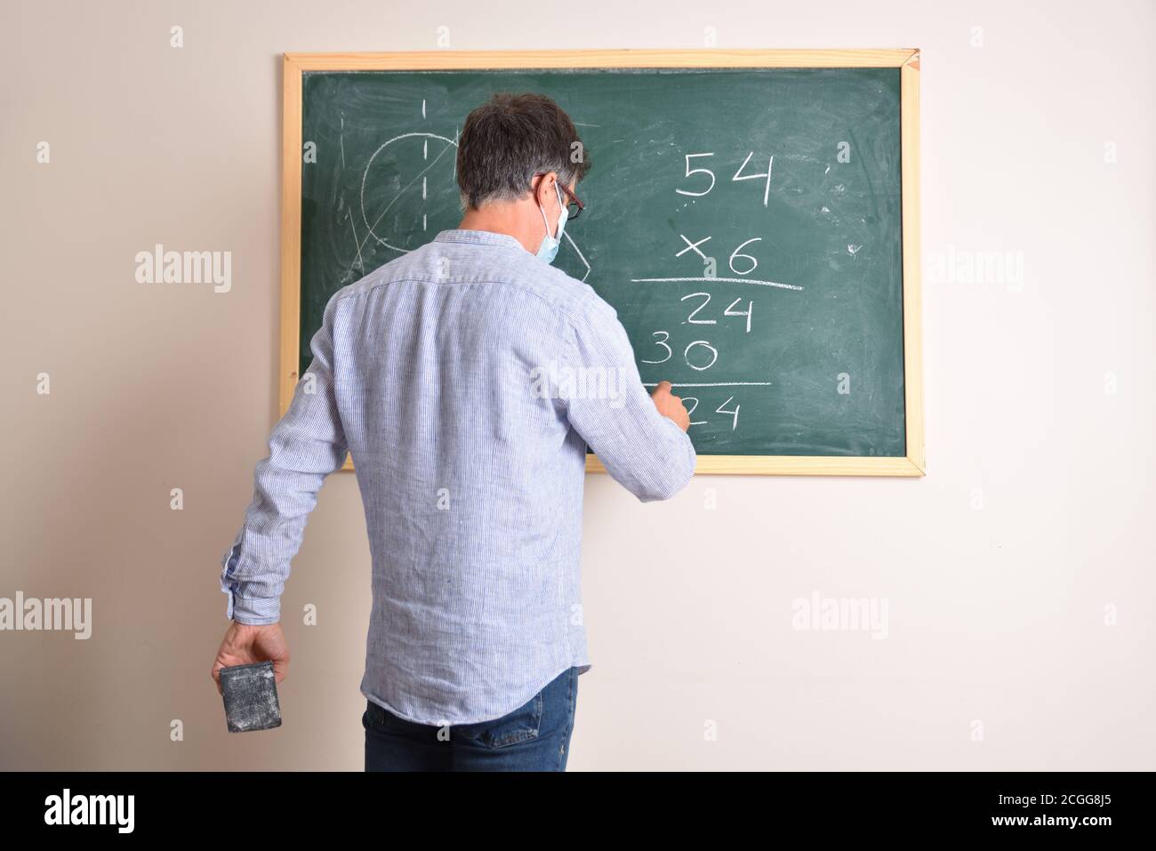 Professeur d'école primaire protégé avec un masque en raison de risque d'infection à coronavirus résolvant la multiplication dans la classe Banque D'Images