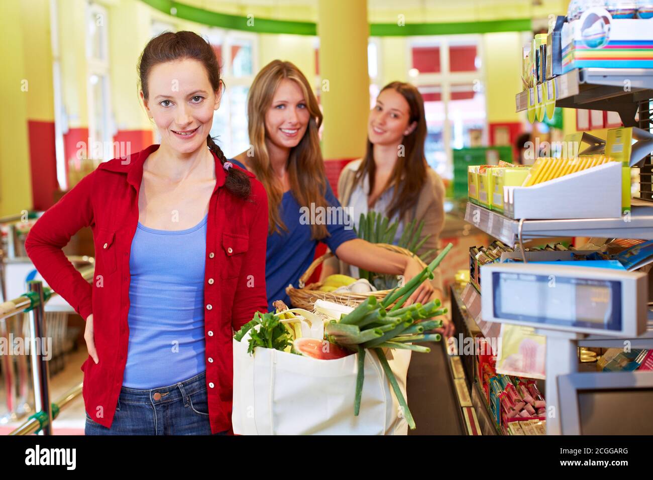 Femme âgée souriante avec des files d'attente de paniers à la caisse du supermarché Banque D'Images