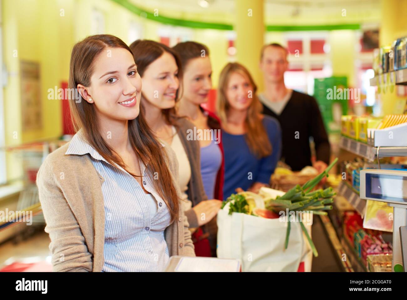 Une femme souriante se tient dans une file d'attente à la caisse un supermarché Banque D'Images