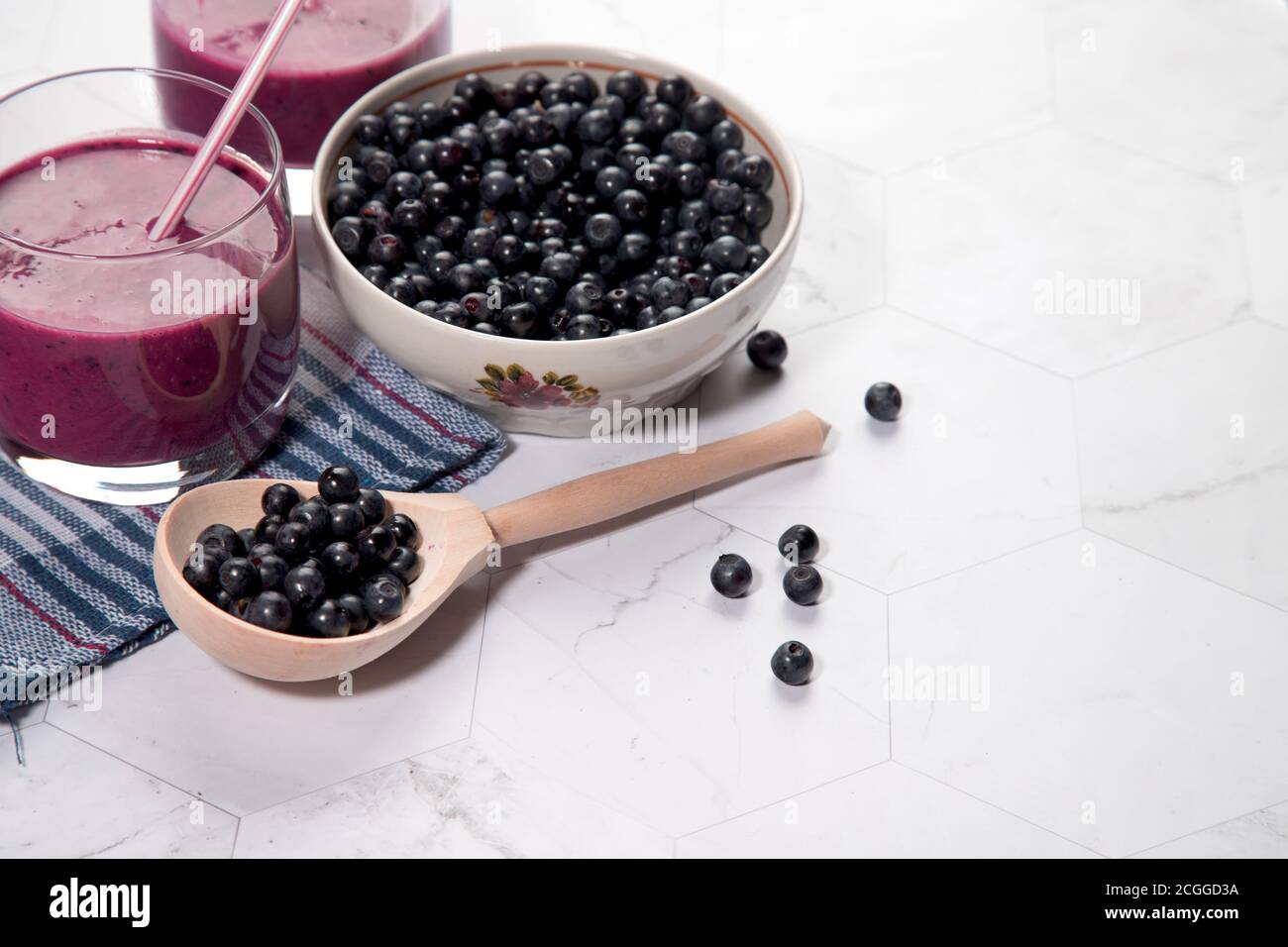 Sur un fond clair est une grande plaque avec des bleuets, deux verres avec un régime de bleuets smoothie stand sur un fond clair, une cuillère en bois avec be Banque D'Images