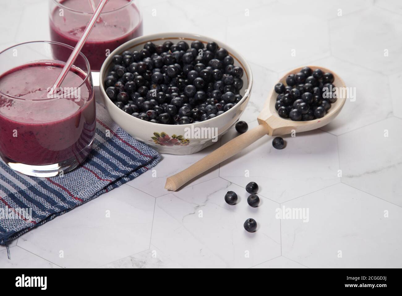 Sur un fond clair est une grande plaque avec des bleuets, deux verres avec un régime de bleuets smoothie stand sur un fond clair, une cuillère en bois avec be Banque D'Images