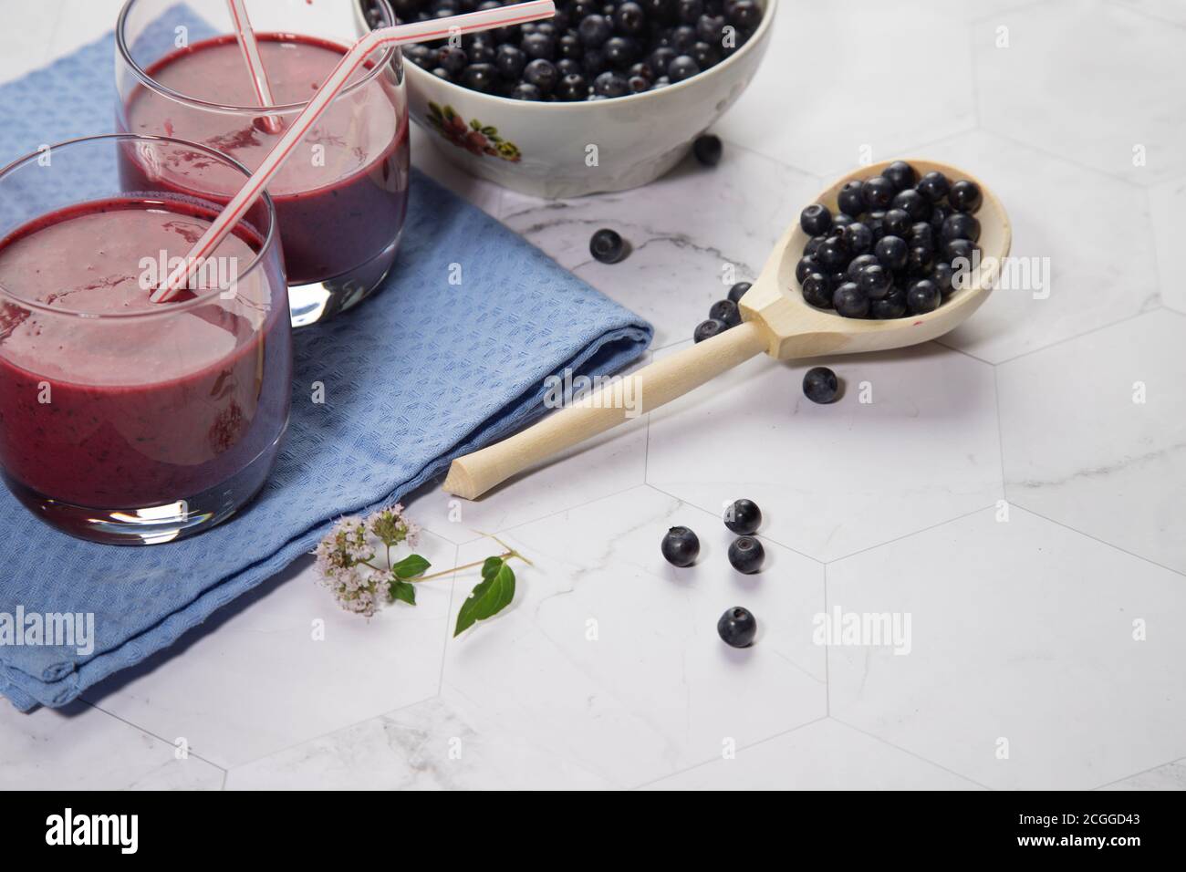 Sur un fond clair est une grande plaque avec des bleuets, deux verres avec un régime de bleuets smoothie stand sur un fond clair, une cuillère en bois avec be Banque D'Images
