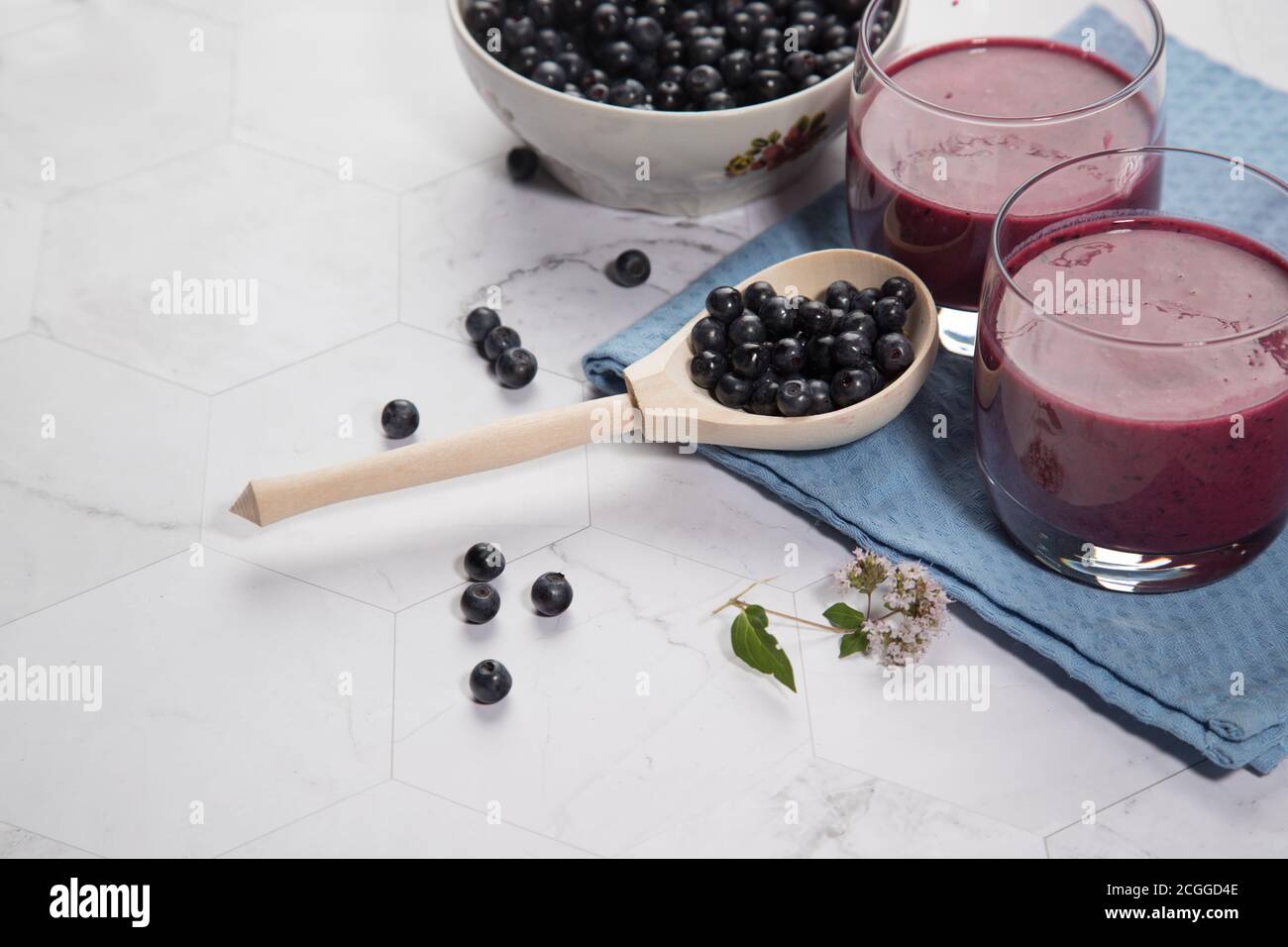 Sur un fond clair est une grande plaque avec des bleuets, deux verres avec un régime de bleuets smoothie stand sur un fond clair, une cuillère en bois avec be Banque D'Images