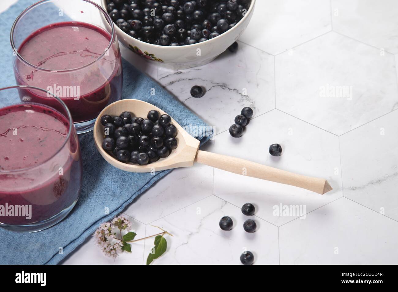 Sur un fond clair est une grande plaque avec des bleuets, deux verres avec un régime de bleuets smoothie stand sur un fond clair, une cuillère en bois avec be Banque D'Images
