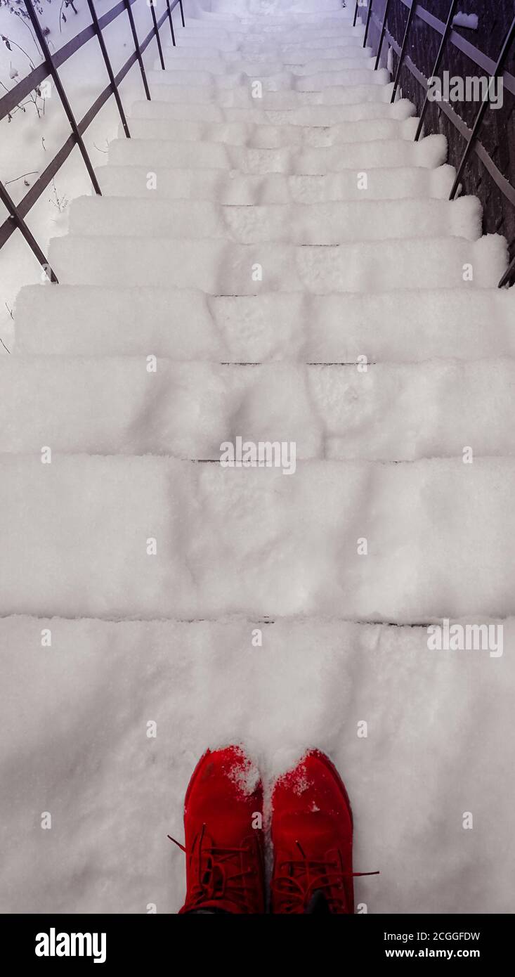 Bottes rouges sur les escaliers couverts de neige Banque D'Images