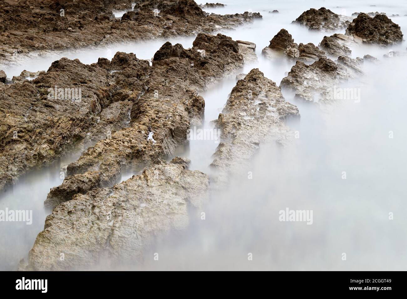 Photographie en exposition longue avec filtre de densité neutre. Plage dans les Asturies, Espagne avec un lever de soleil nuageux. Banque D'Images