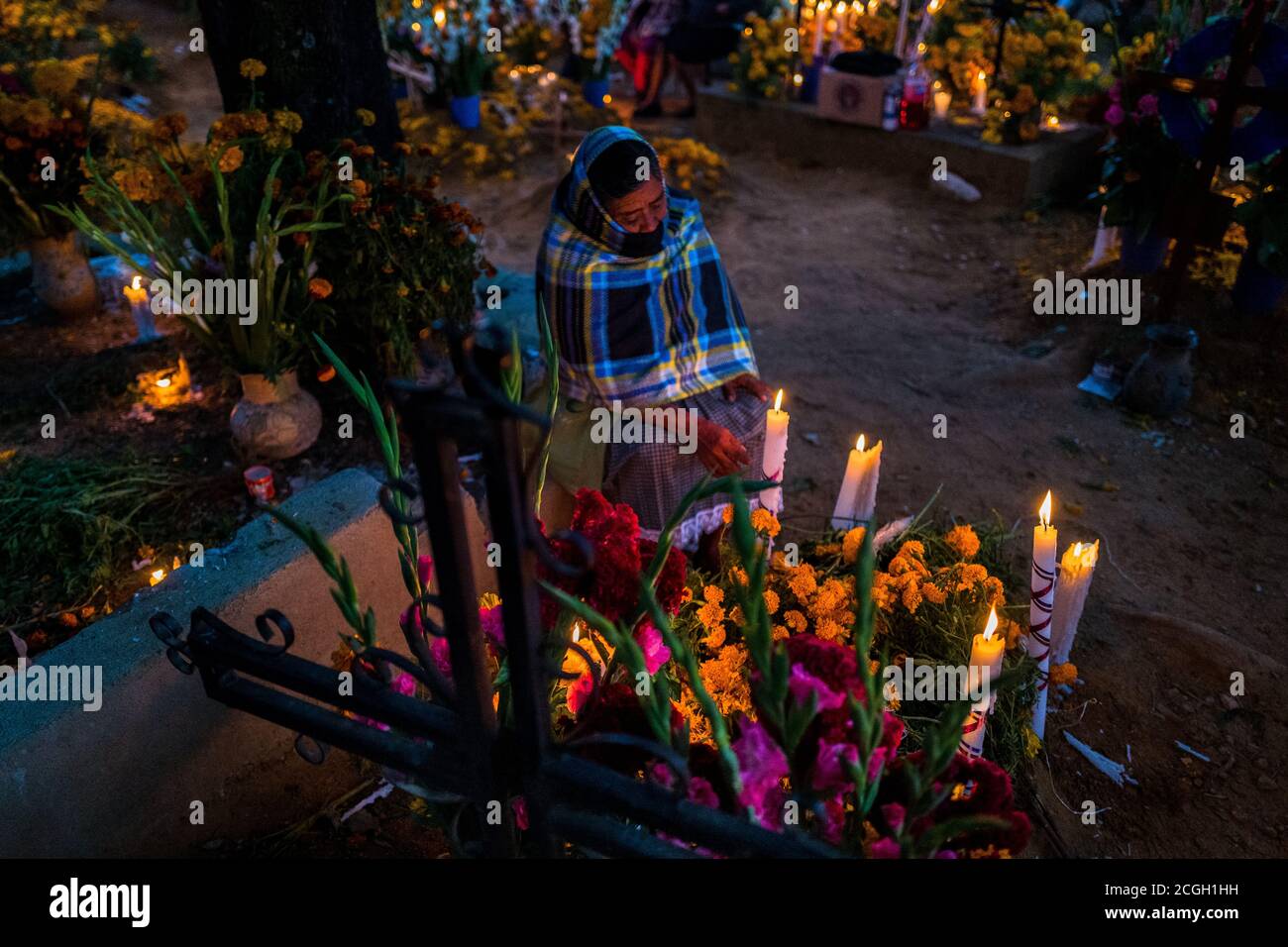 Une mexicaine est assise sur la tombe ornée de fleurs pour honorer ses parents décédés pendant les festivités du jour des morts à Oaxaca, au Mexique. Banque D'Images