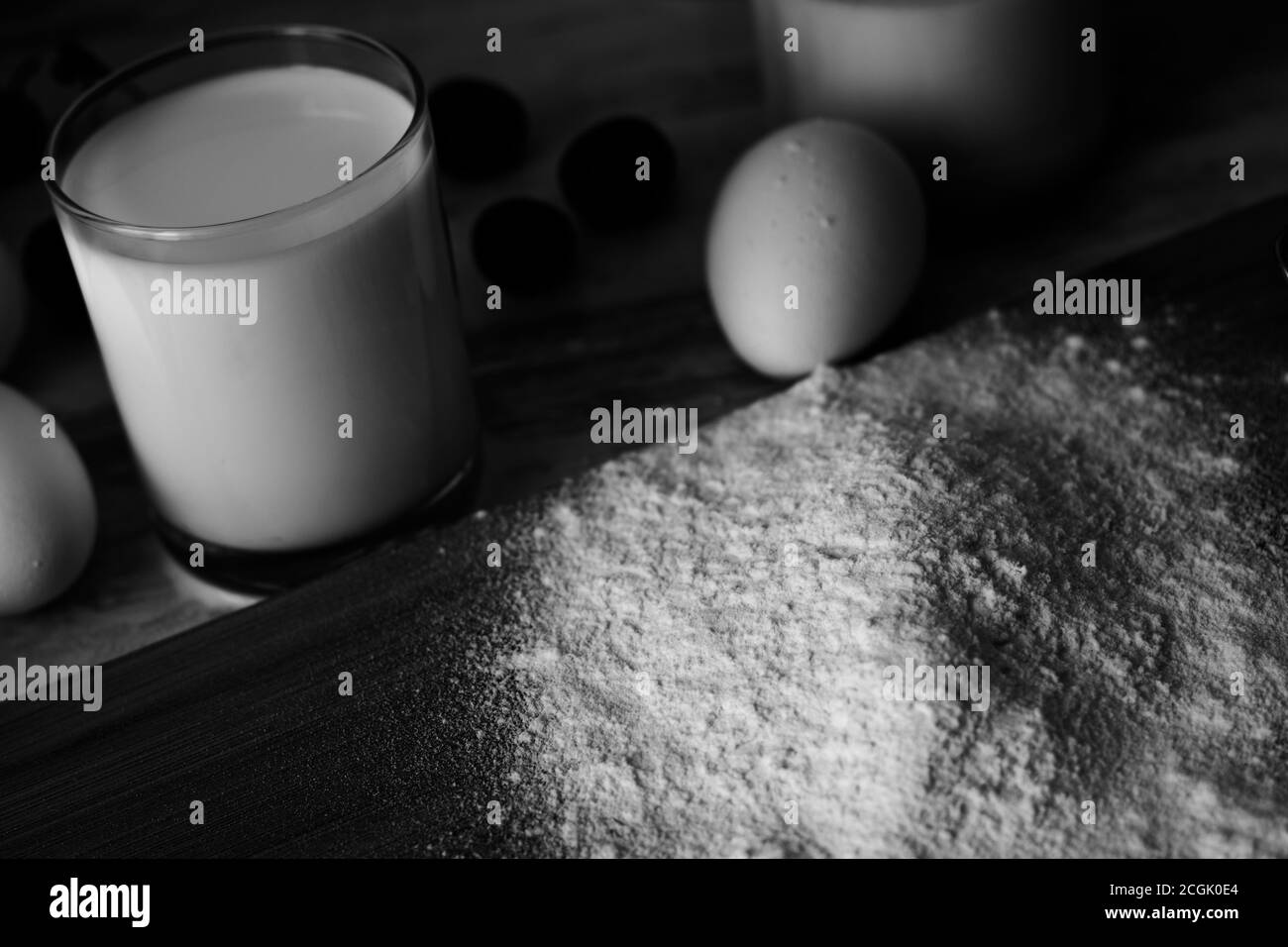 Photo en noir et blanc de la farine, des œufs, du lait et des baies Banque D'Images