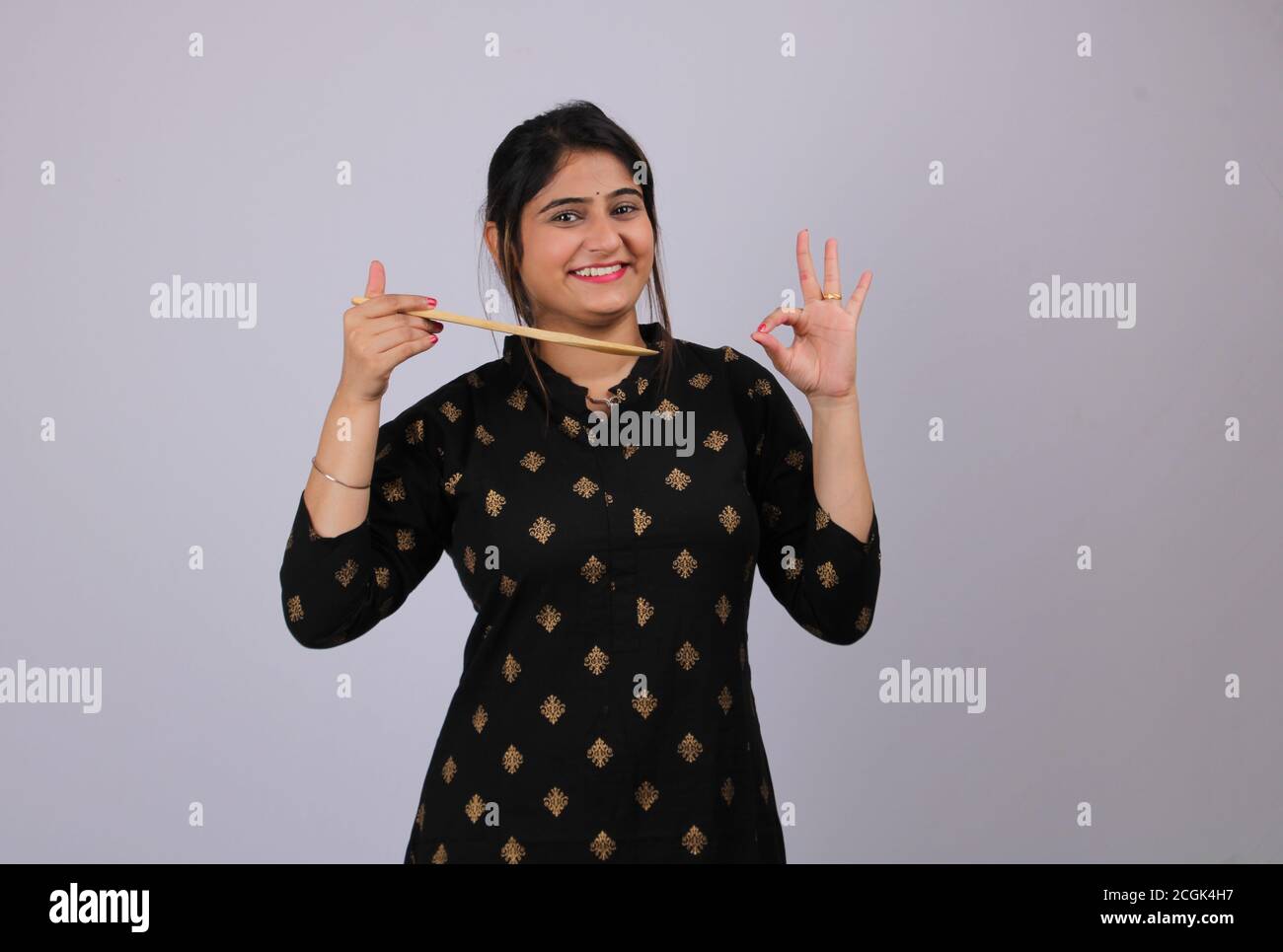 Belle fille indienne ou femme ou maison fabricant tenant une cuillère de service ou des ustensiles de cuisine à la main. Banque D'Images