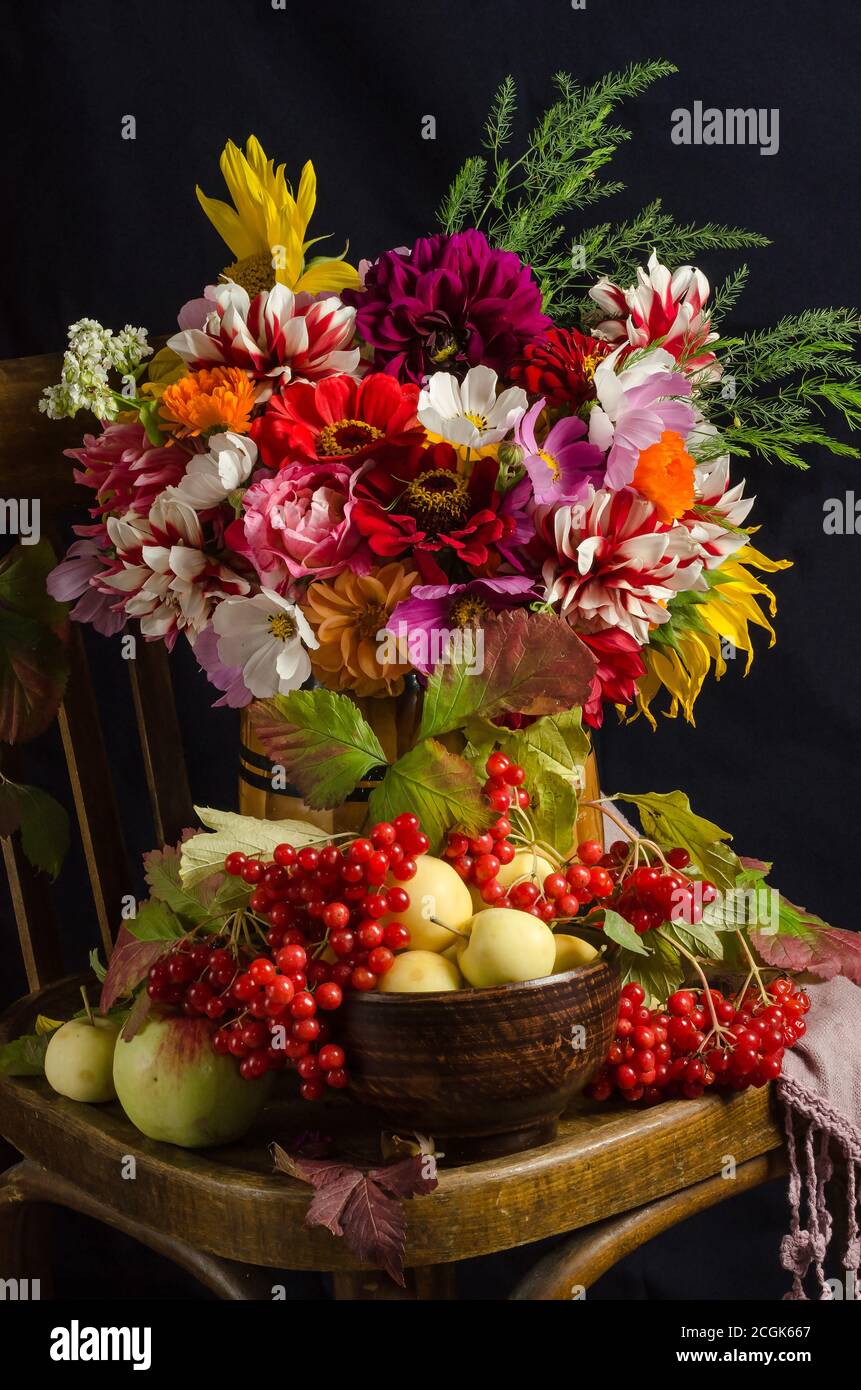 L'atmosphère de l'automne encore la vie avec un beau bouquet coloré de fleurs de jardin, baies rouges, pommes, feuilles d'automne sur fond noir. Banque D'Images