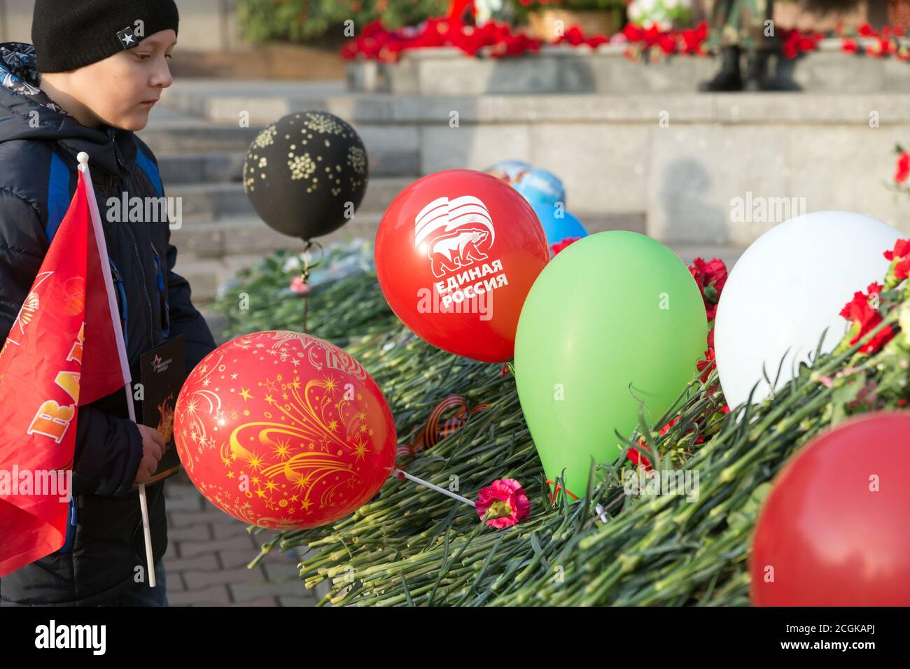 Garçon avec un drapeau rouge regarde les balles avec L'emblème du parti Russie unie Banque D'Images