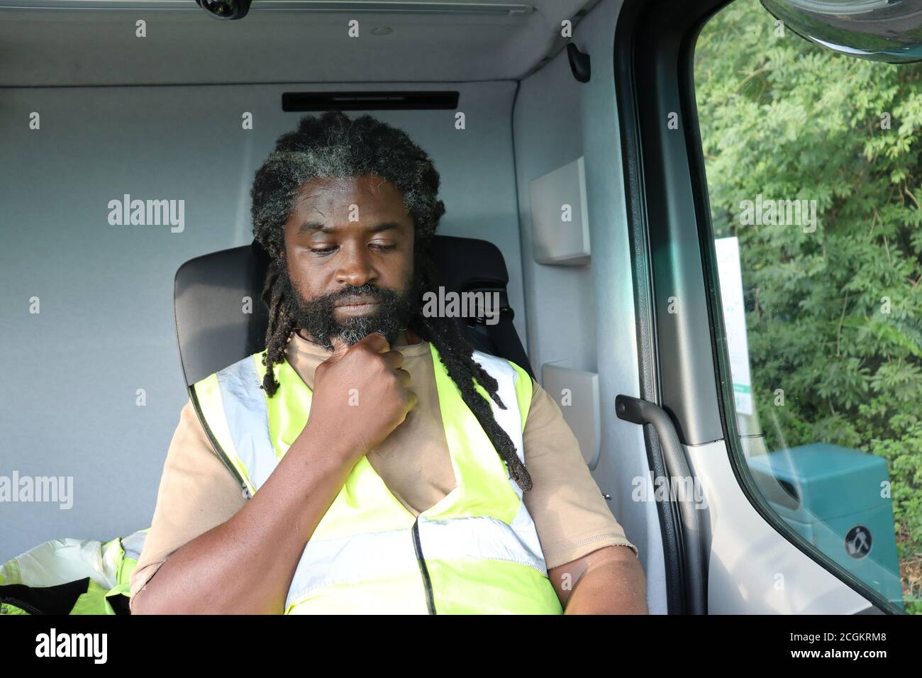 Conducteur de camion dans la cabine en pause après un long trajet. Homme regardant vers le bas le téléphone mobile. Banque D'Images
