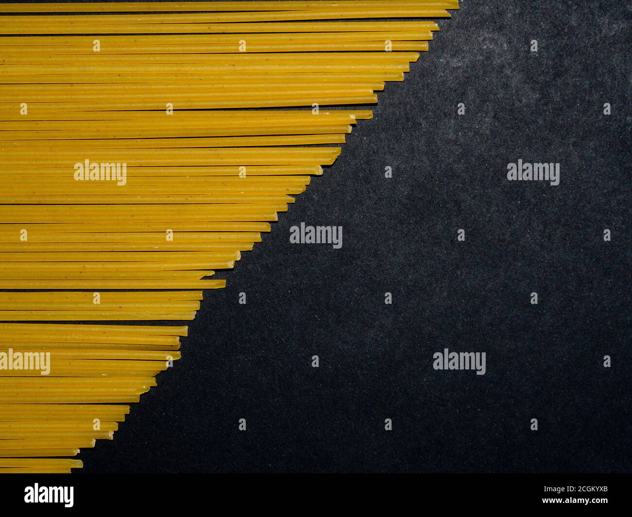 Spaghetti crus. Pâtes disposées dans un motif géométrique sur fond noir. Concept de menu. Arrière-plan du texte. Banque D'Images