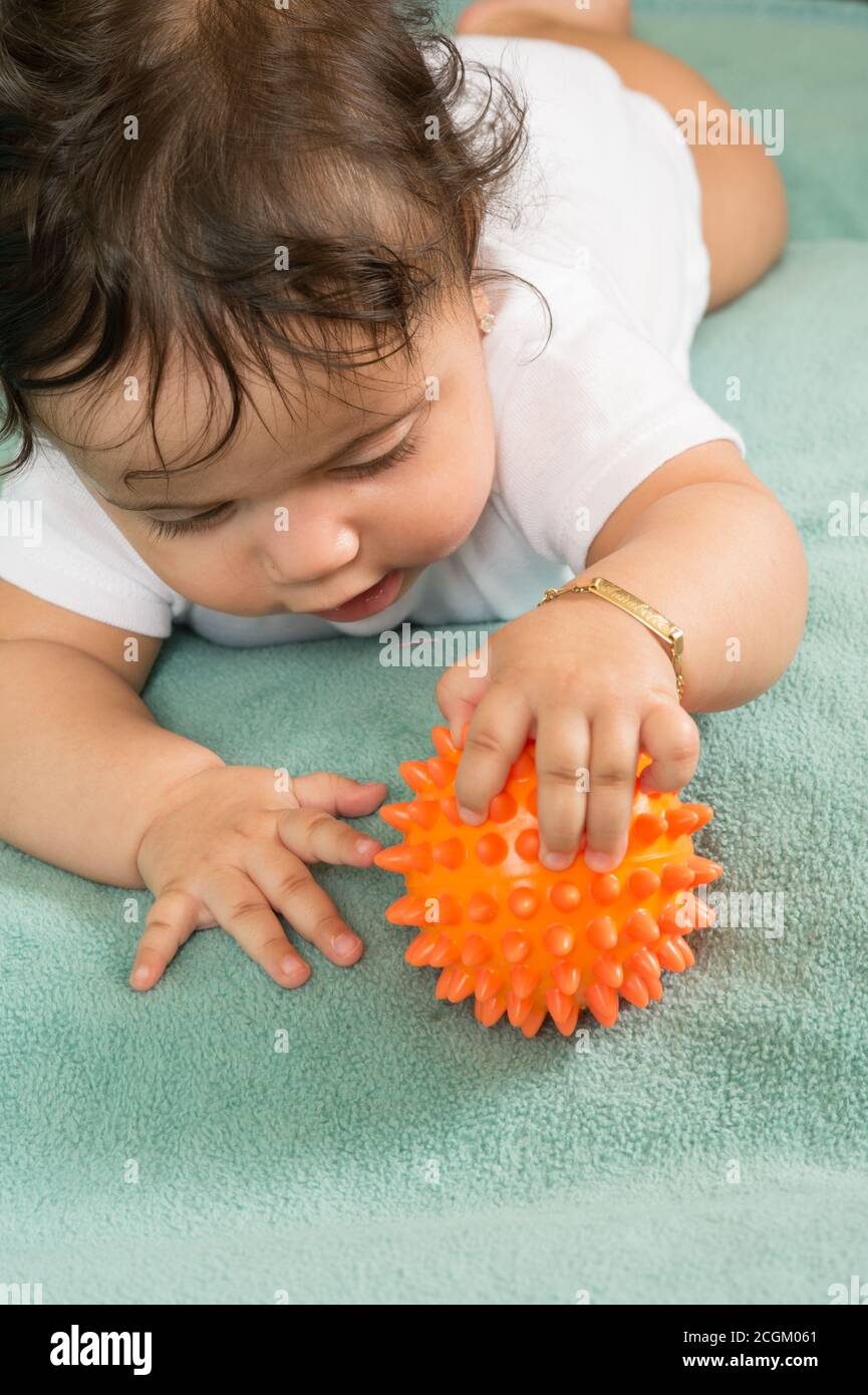 Bebe Fille De 6 Mois Sur L Estomac Gros Plan Tenir Et Explorer La Balle En Plastique Bosselee Photo Stock Alamy