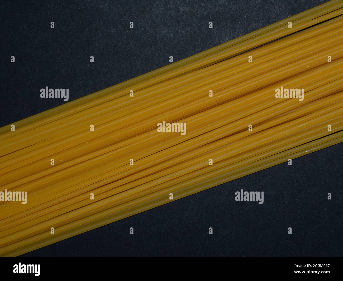 Spaghetti crus. Pâtes disposées dans un motif géométrique sur fond noir. Concept de menu. Arrière-plan du texte. Banque D'Images