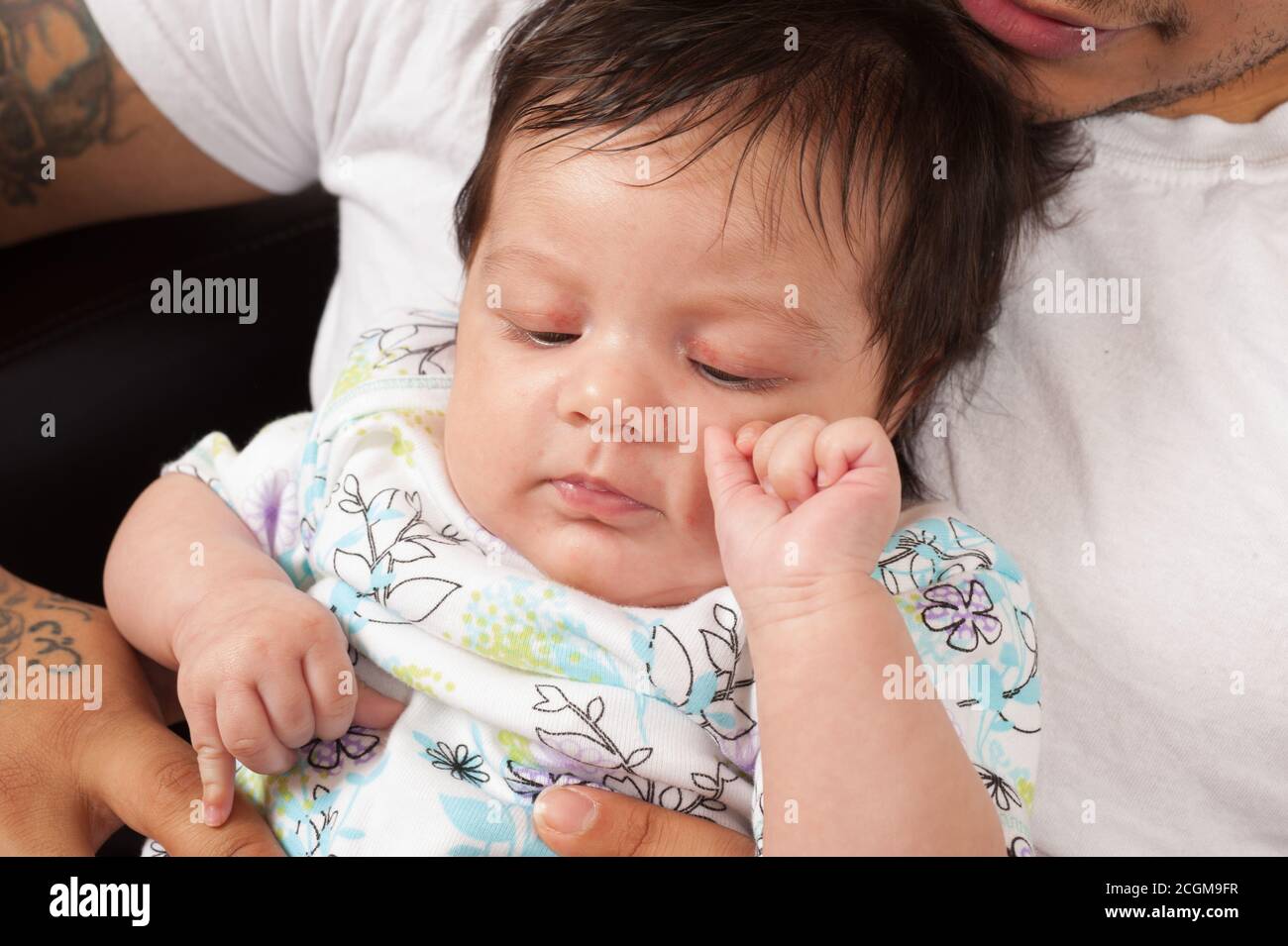 nouveau-né bébé fille un mois gros plan tenu par le jeune père, son petit doigt touchant sa main, détendu, heureux, horizontal Banque D'Images