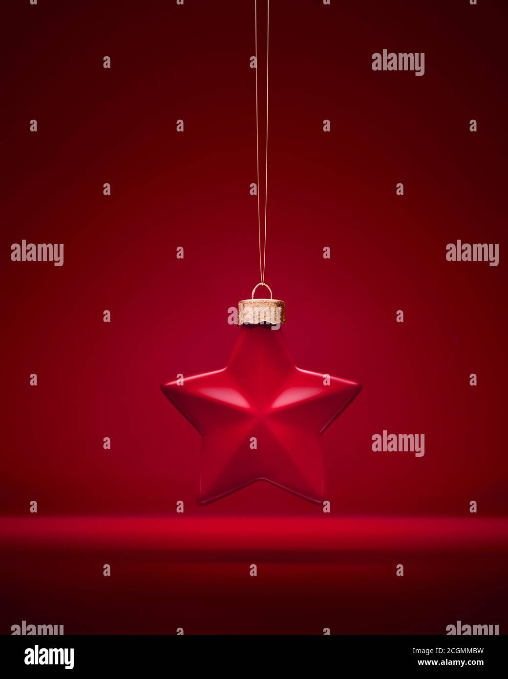 Décoration de Noël mate rouge Bourgogne. Boule en forme d'étoile à cinq pointes accrochée à une ficelle dorée. Arrière-plan rouge. Décoration de Noël, ambiance festive conc Banque D'Images