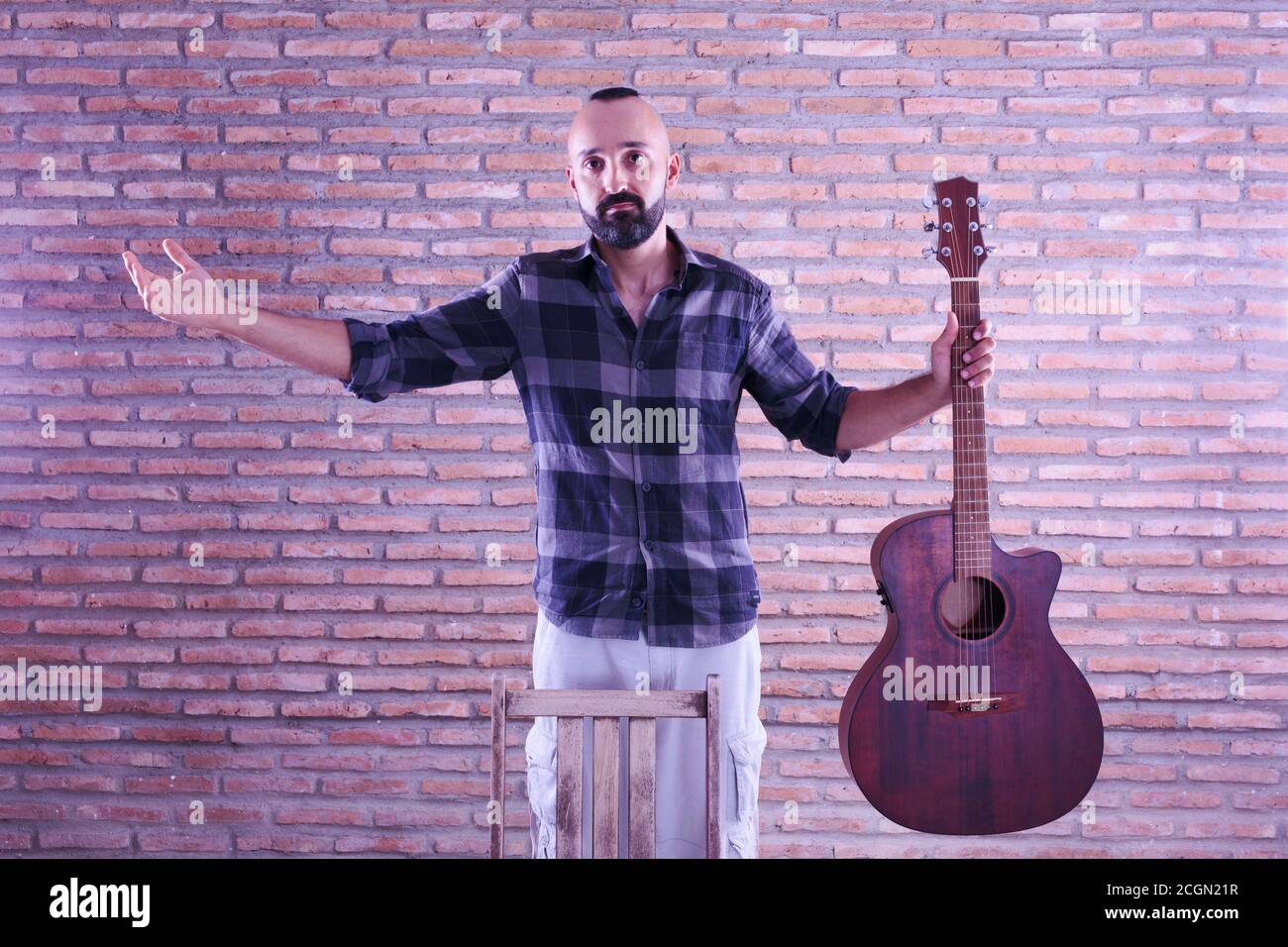 Fier jeune homme adulte tenant une guitare acoustique après un spectacle. Banque D'Images