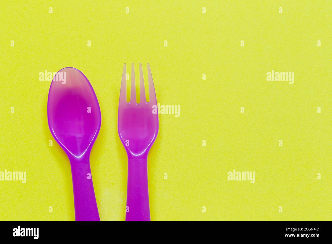 Cuillère et fourchette violettes sur fond jaune et espace de copie pour le design dans votre travail. Banque D'Images