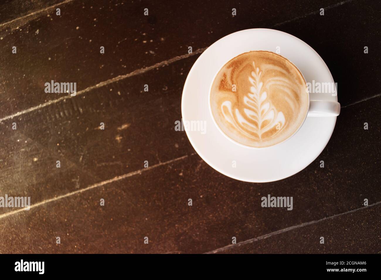 Café chaud avec art latte sur une table en bois au café Banque D'Images