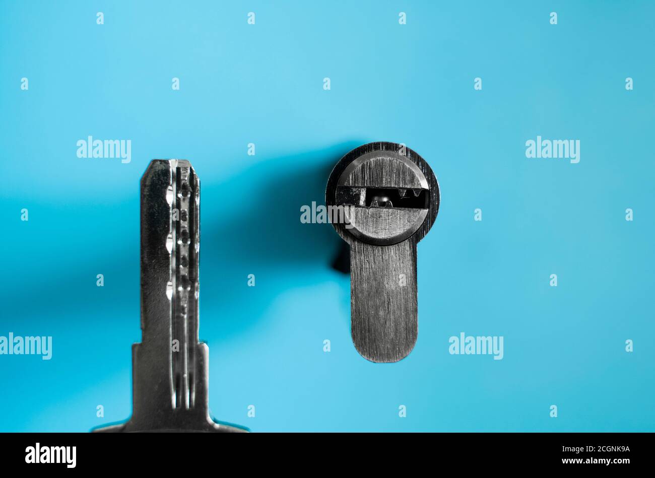 Un barillet de serrure de porte avec clé sur fond bleu. Le barillet de  serrure avec la clé. Installation d'une nouvelle serrure sur la porte.  Pièces de rechange pour le Photo Stock -